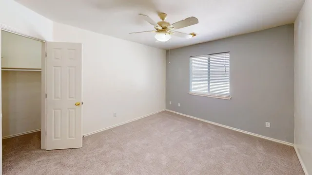 an empty room with windows and fan