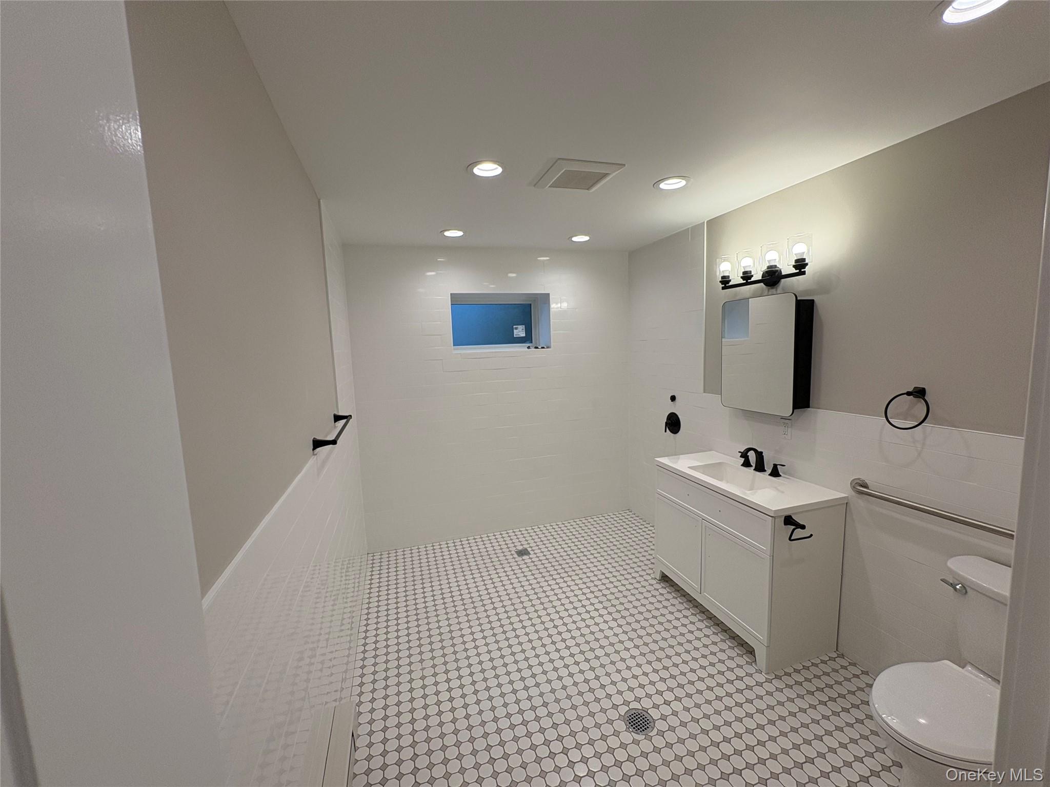 455 Sunrise Highway, Unit 1A West Babylon, NY 11704 - Photo 12 of 15 a bathroom with a sink a toilet and mirror