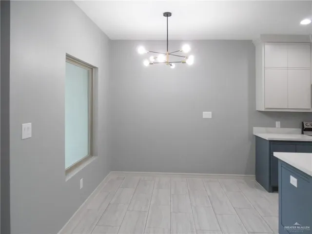 a view of empty room with wooden floor and kitchen view