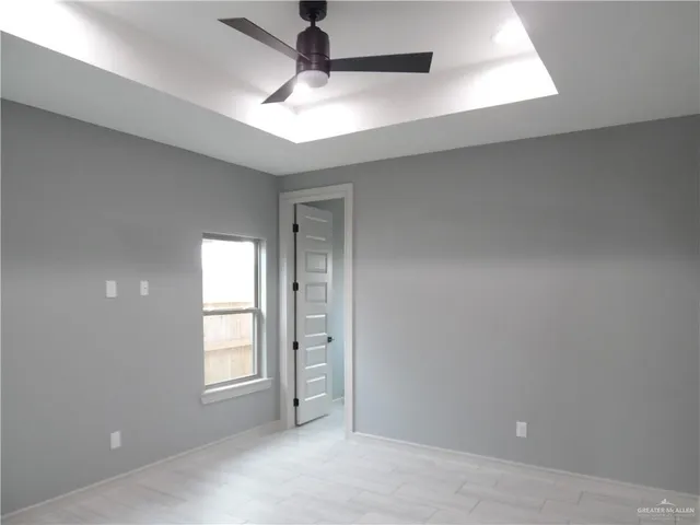 an empty room with windows and fan
