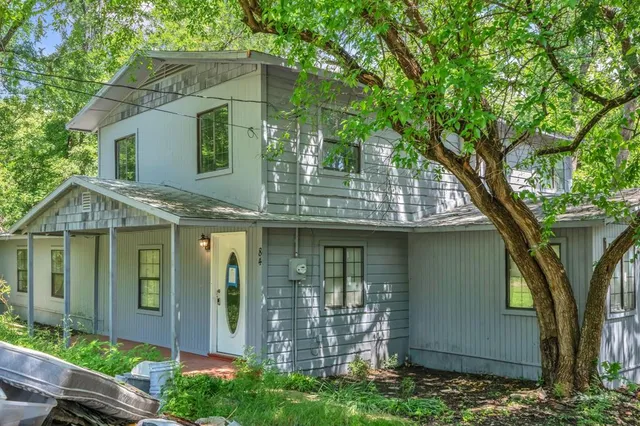 a view of a white house with large windows and a large tree