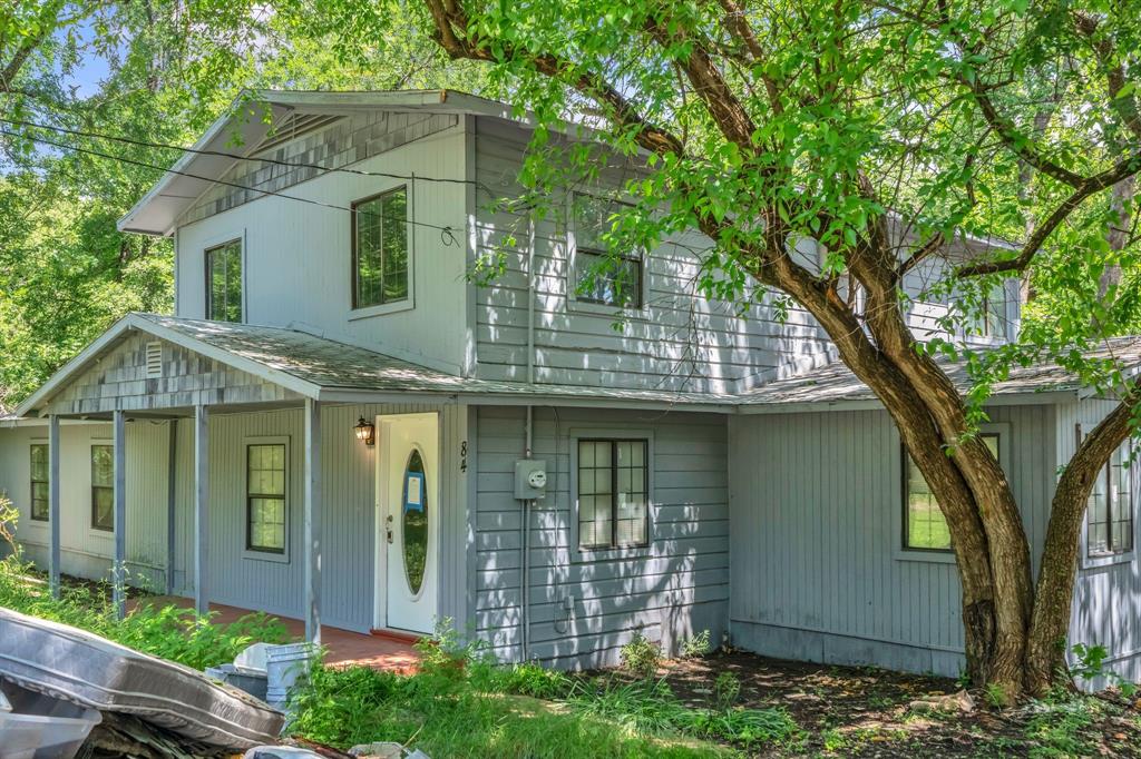 84 Natchez Road Pottsboro, TX 75076 - Photo 2 of 37 a view of a white house with large windows and a large tree