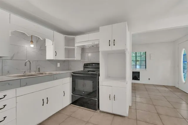a kitchen with white cabinets and appliances