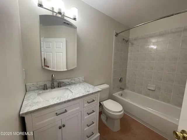 a bathroom with a granite countertop sink a toilet and shower
