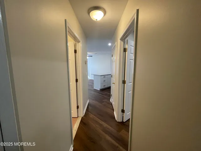 a view of a hallway with a livingroom and a bathroom with a sink