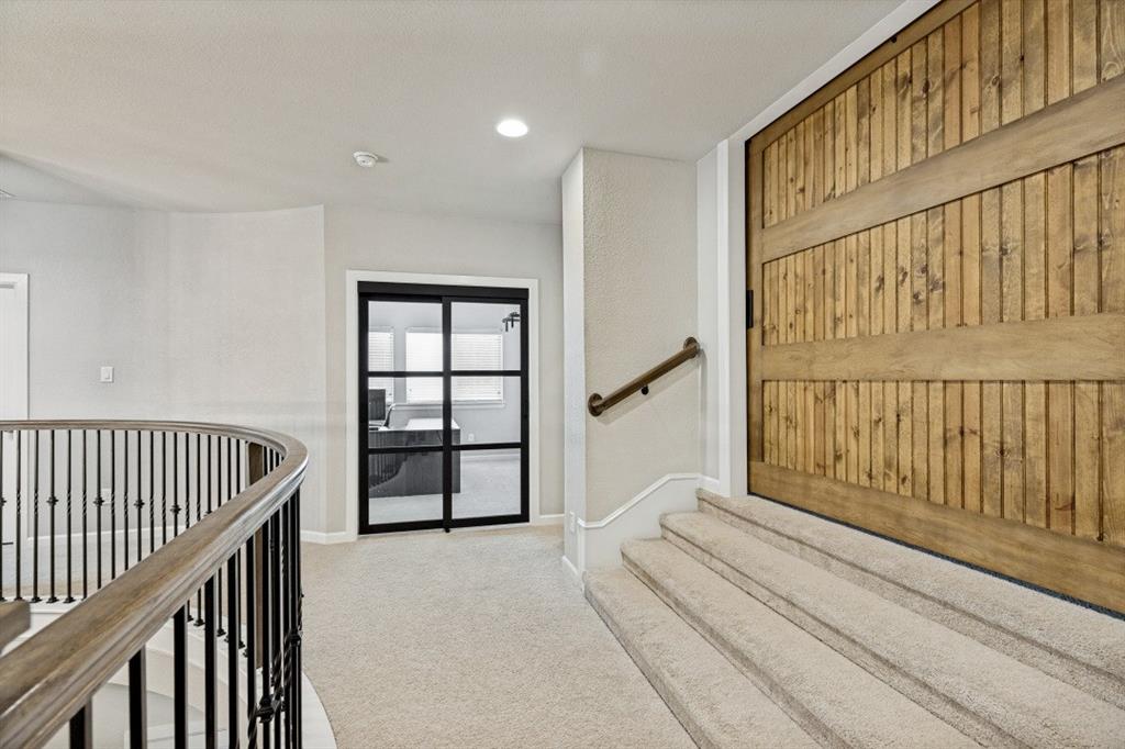 2721 Old Shire Path Road Prosper, TX 75078 - Photo 23 of 40 Carpeted staircase with a wood handrail, metal balusters, and a large wood barn door