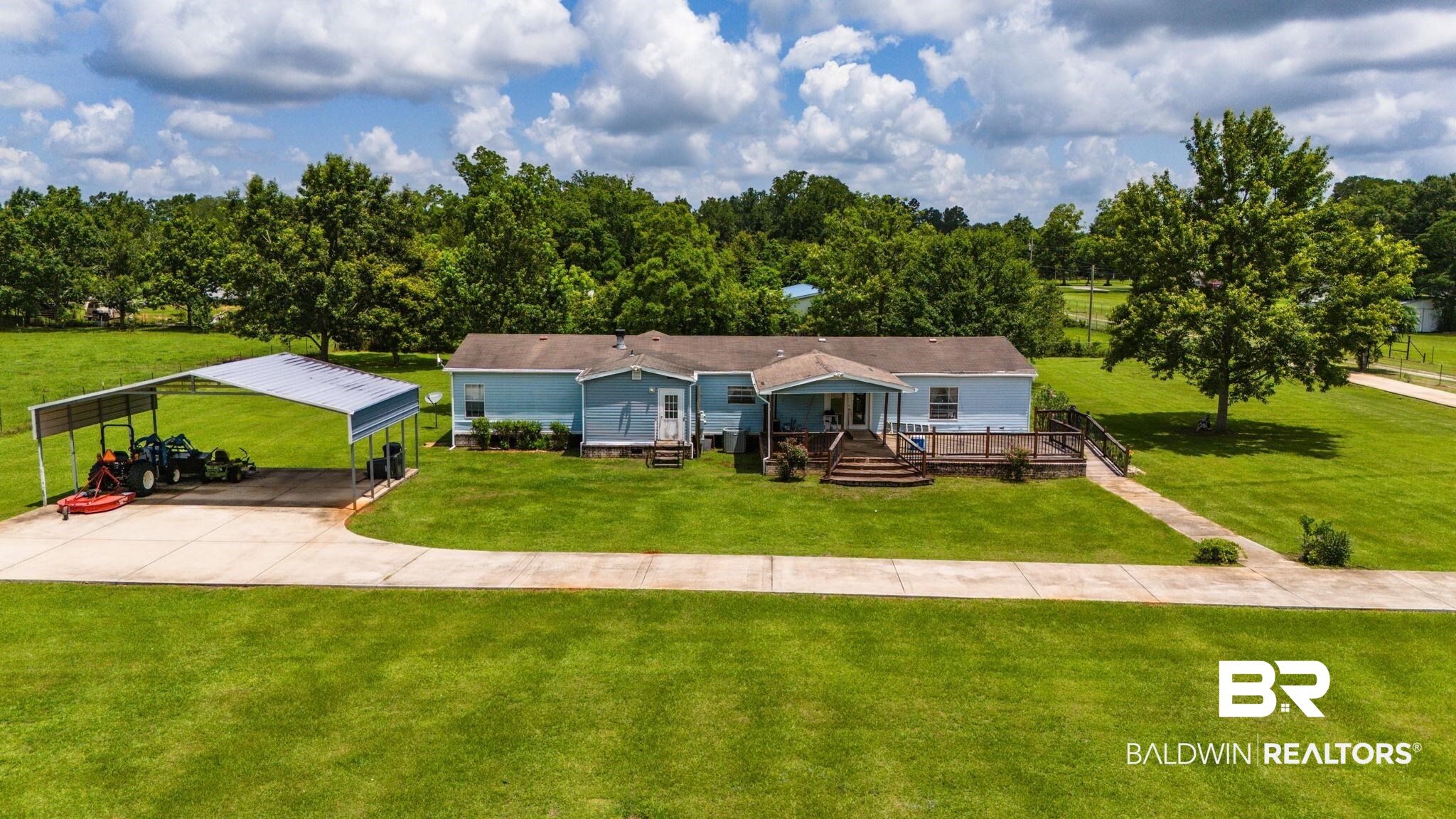 34985b Spring Road South, Unit B Stapleton, AL 36578 - Photo 1 of 31 Light blue exterior with covered porch entry, expansive green lawn, substantial metal carport, and paved driveway