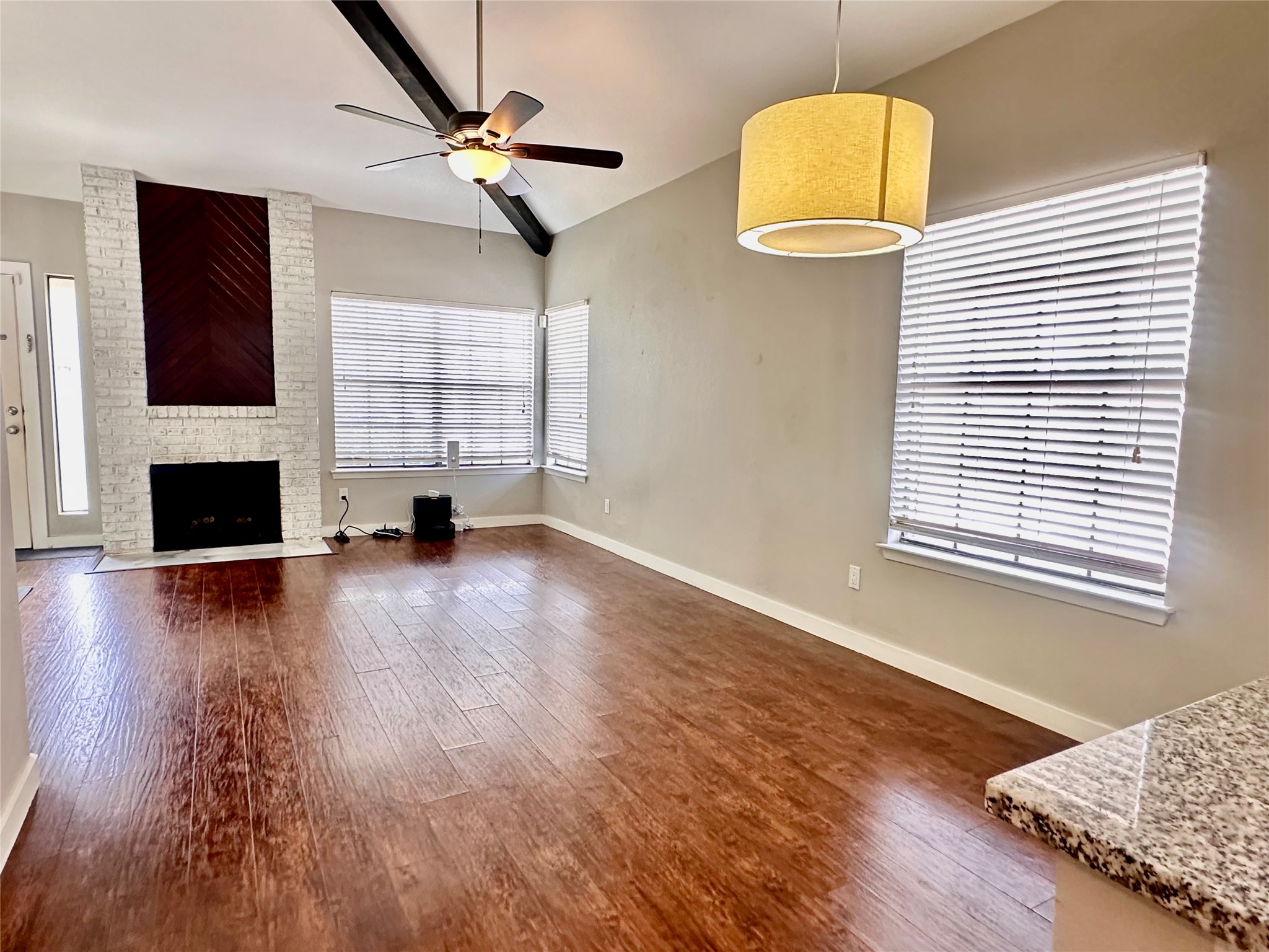 1748 Ohlen Road, Unit 22 Austin, TX 78757 - Photo 3 of 14 Spacious living area featuring vaulted ceilings with exposed beams, wood-finish flooring, and a white brick fireplace with a dark wood inlay