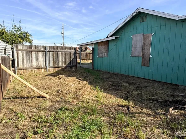 a backyard of a house with wooden fence table and chairs