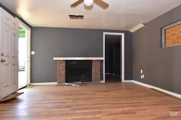 a view of an empty room with wooden floor and a fireplace