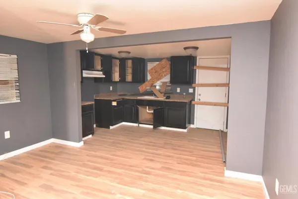 a view of kitchen and empty room with wooden floor