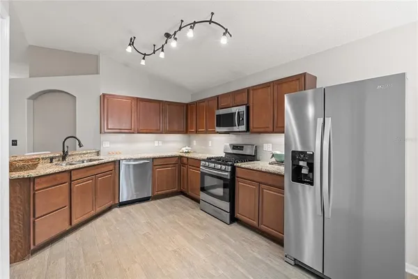 a kitchen with stainless steel appliances granite countertop a refrigerator a stove top oven a sink and dishwasher