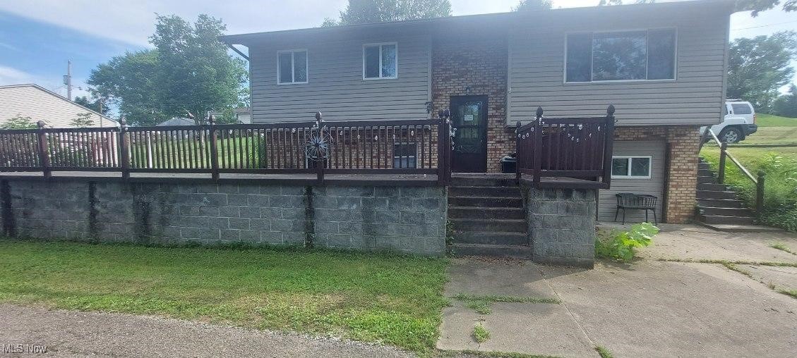 7 Montenery Road Rayland, OH 43943 - Photo 2 of 29 Rear view of property with stairway, an attached garage, brick siding, driveway, and a lawn