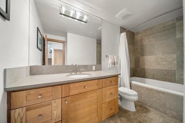 a bathroom with a granite countertop sink a toilet a mirror and shower