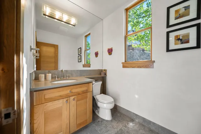 a bathroom with a granite countertop toilet a sink and a mirror