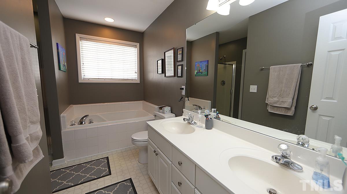 8604 Clivedon Drive Raleigh, NC 27615 - Photo 12 of 16 a bathroom with a tub a sink and mirror
