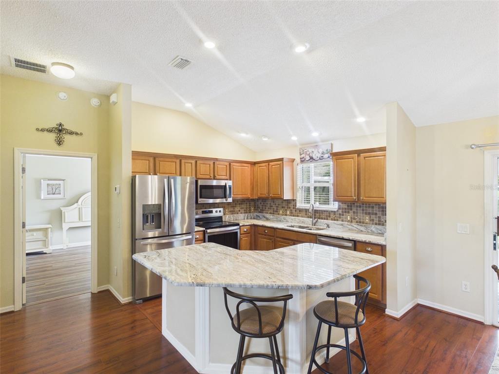 2297 Welcome Way The Villages, FL 32162 - Photo 13 of 36 a kitchen with granite countertop kitchen island cabinets and wooden floor