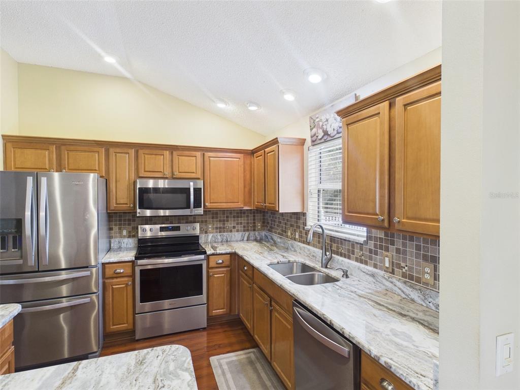 2297 Welcome Way The Villages, FL 32162 - Photo 14 of 36 a kitchen with stainless steel appliances granite countertop a sink stove and refrigerator