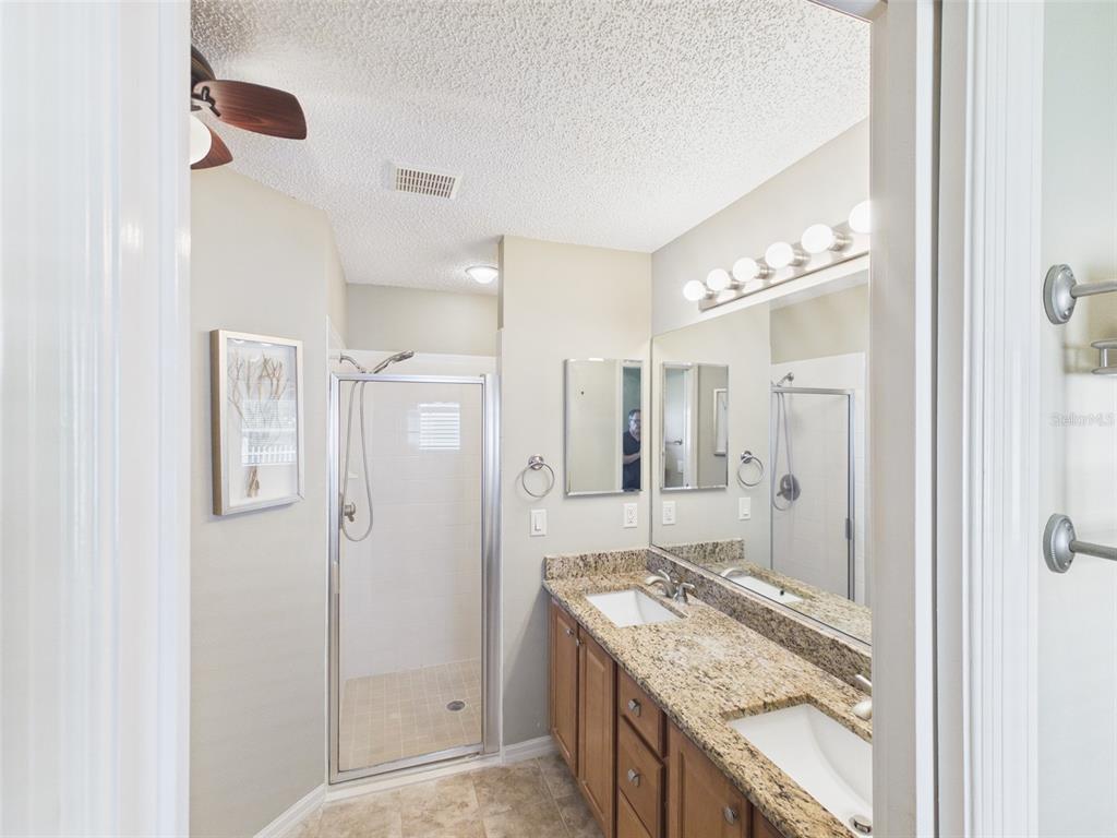 2297 Welcome Way The Villages, FL 32162 - Photo 22 of 36 a bathroom with a granite countertop sink a mirror a shower and vanity