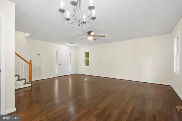 a view of an empty room with wooden floor and a chandelier