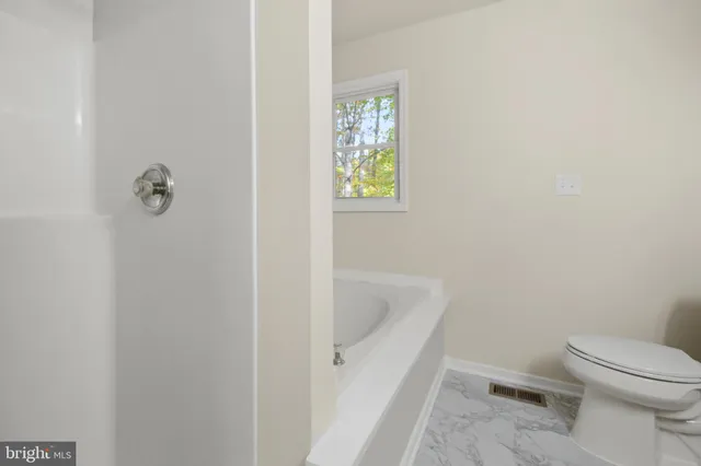 a white toilet sitting next to a bath tub