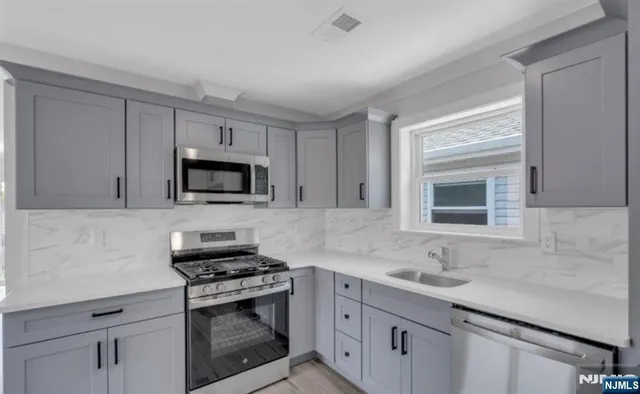a kitchen with white cabinets sink and stainless steel appliances
