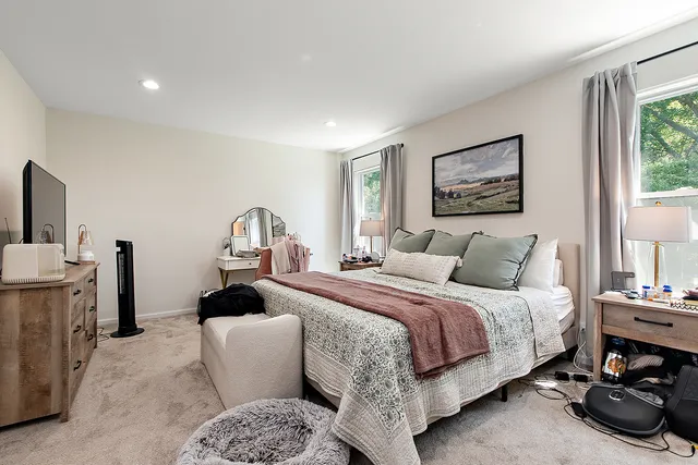 a bedroom with bed a mirror and a window