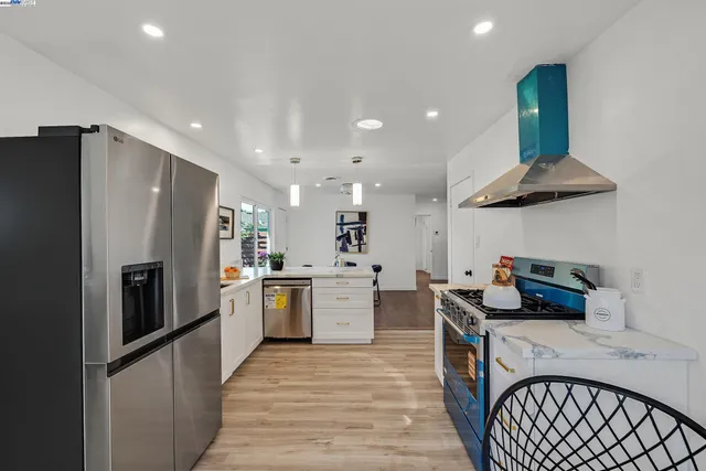 a kitchen with a refrigerator a sink dishwasher a stove and a dining table with wooden floor