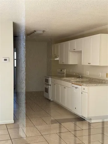 a kitchen with granite countertop white cabinets and stainless steel appliances