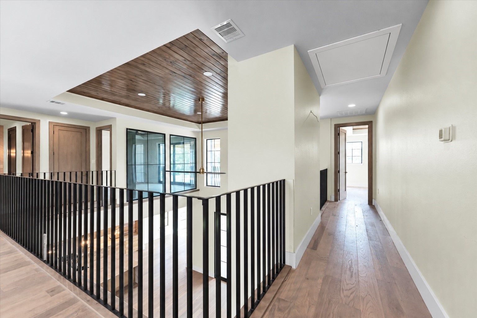 23701 Birch Grove Road Montgomery, TX 77316 - Photo 27 of 50 Elegant hallway with sleek black railings, warm wood accents, and ample natural light from large windows.