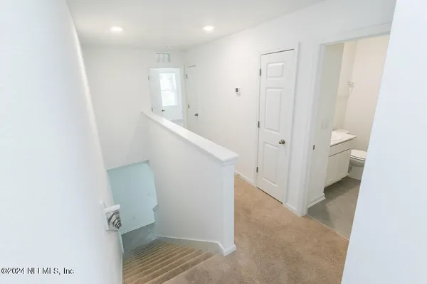 a view of a hallway with bathroom and wooden floor