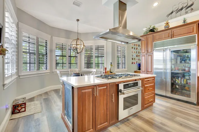 a kitchen with stainless steel appliances a stove a sink dishwasher a dining table and chairs with wooden floor