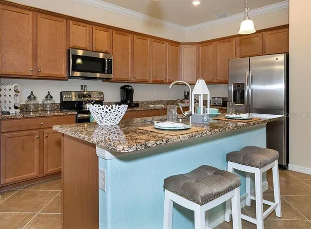 a kitchen with stainless steel appliances granite countertop a sink a stove a refrigerator cabinets and chairs