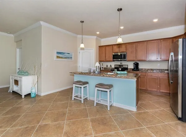 a kitchen with stainless steel appliances a sink a stove a microwave a center island and cabinets
