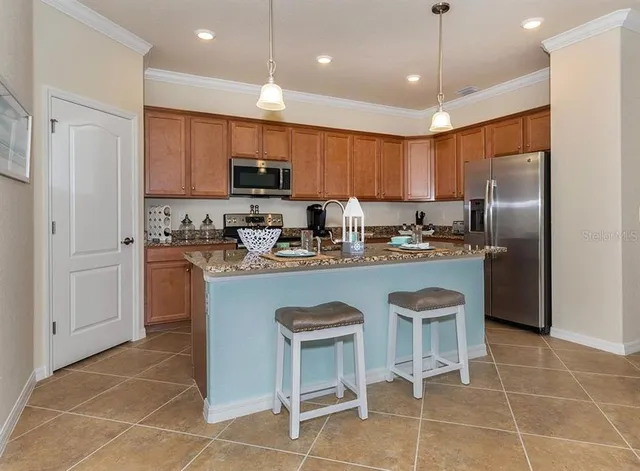 a kitchen with stainless steel appliances granite countertop a sink a stove a refrigerator cabinets and chairs