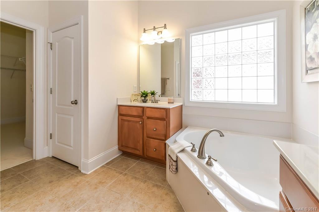 10944 Round Rock Road Charlotte, NC 28277 - Photo 17 of 23 a bathroom with a tub a sink a mirror and a window