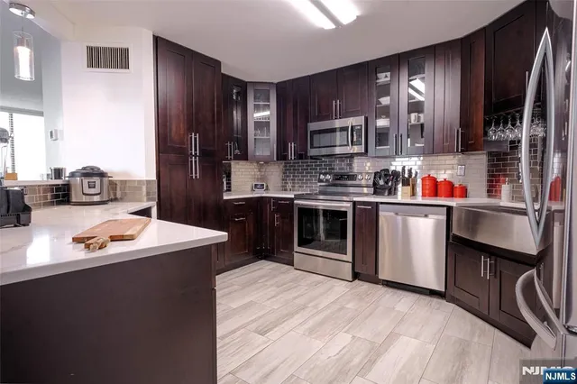 a kitchen with stainless steel appliances granite countertop a sink dishwasher stove top oven and cabinets