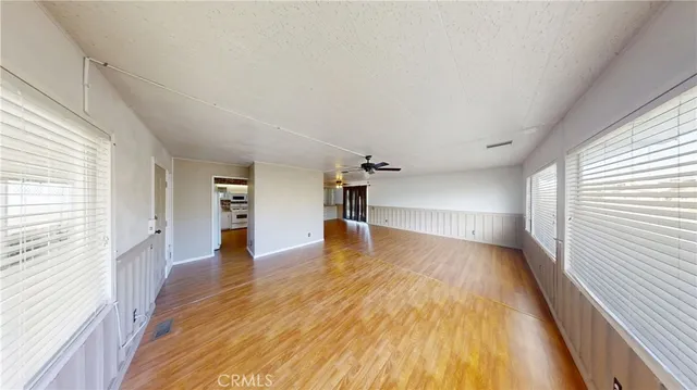 a view of empty room with wooden floor and fan