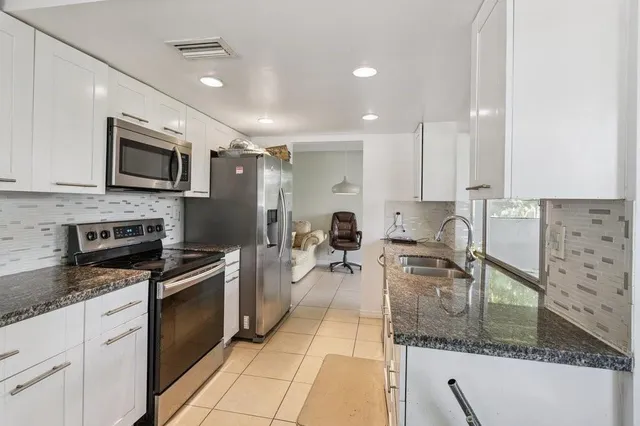a kitchen with stainless steel appliances granite countertop a sink a stove top oven and granite counter tops