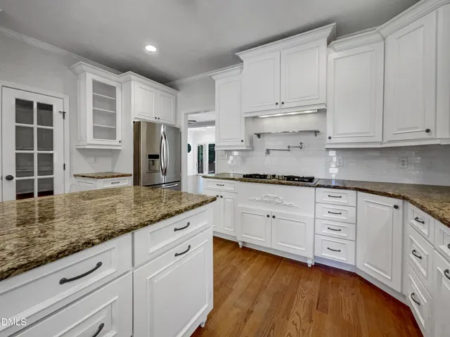 a kitchen with granite countertop white cabinets and white stainless steel appliances