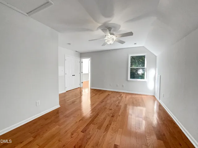 an empty room with wooden floor chandelier fan and windows