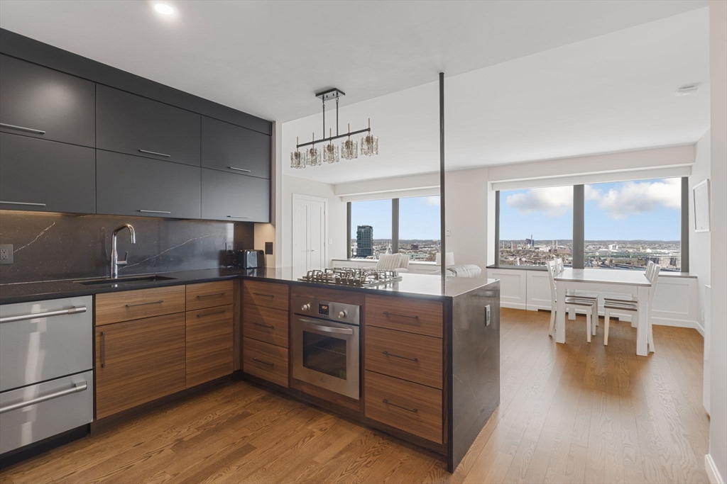 85 East India Row, Unit 38H Boston, MA 02110 - Photo 1 of 15 a kitchen with stainless steel appliances granite countertop a stove a sink and white cabinets with wooden floors