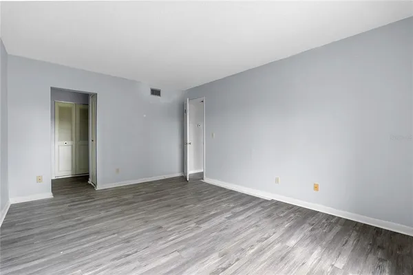 a view of an empty room with wooden floor and closet