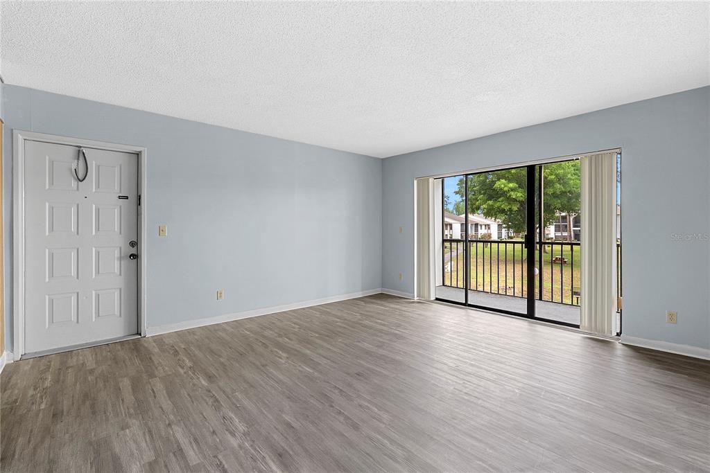 8203 Sun Spring Circle, Unit 62 Orlando, FL 32825 - Photo 3 of 19 a view of an empty room with wooden floor and a window