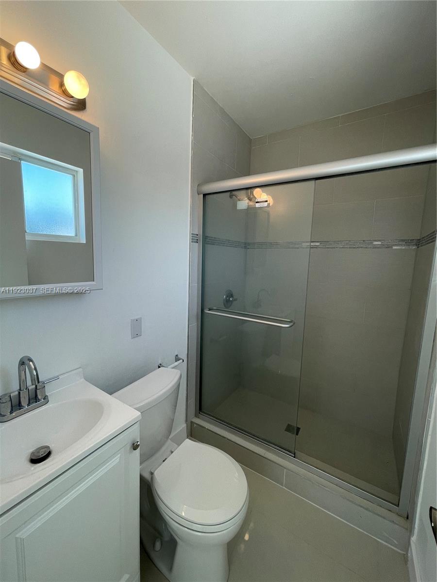 8215 Crespi Boulevard, Unit 4 Miami Beach, FL 33141 - Photo 20 of 34 a bathroom with a toilet sink vanity and shower