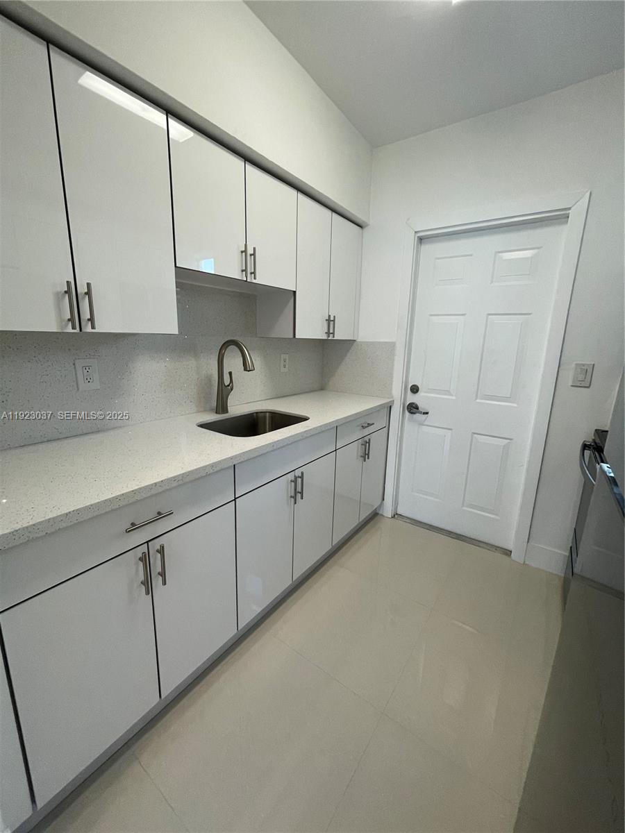 8215 Crespi Boulevard, Unit 4 Miami Beach, FL 33141 - Photo 6 of 34 a kitchen with a sink and cabinets