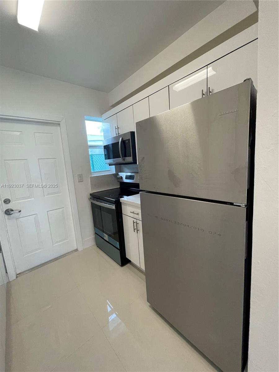 8215 Crespi Boulevard, Unit 4 Miami Beach, FL 33141 - Photo 7 of 34 a kitchen with stainless steel appliances a refrigerator and a stove top oven