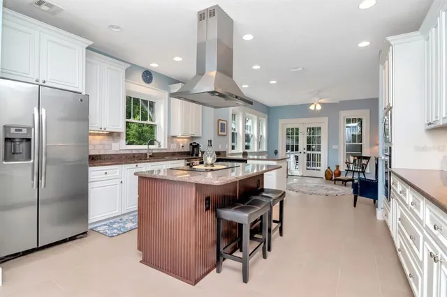 a kitchen with stainless steel appliances granite countertop a refrigerator a sink dishwasher a stove and a refrigerator with wooden floor