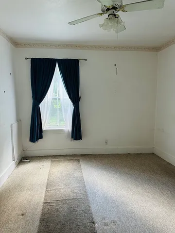 an empty room with windows and refrigerator