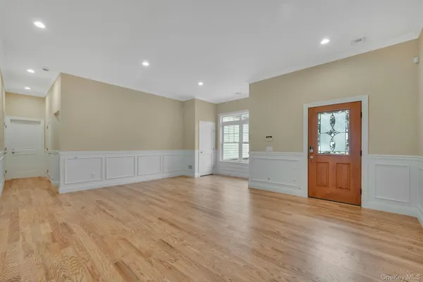 a view of an empty room with wooden floor and windows